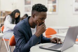 A student is curiously staring at his laptop.iously staring at his laptop.